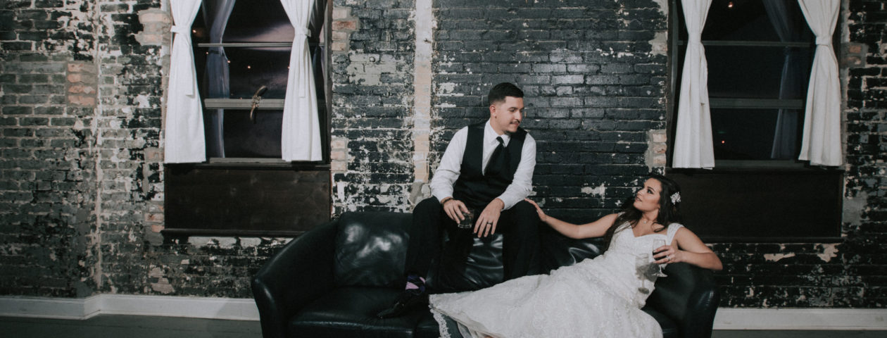 Bride and groom in front of black brick wall